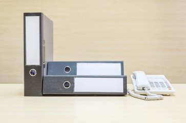 Closeup document file and white phone , office phone on blurred wooden desk and wall textured background in the meeting room under window light