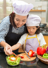 Asian mother teaching daughter making salad in kitchen,Cooking  concept of happy asian little girl and mother making salad 