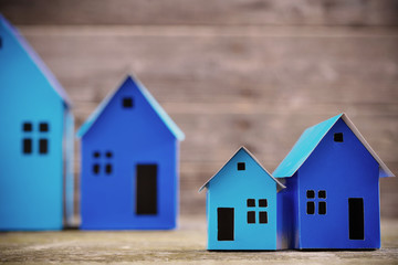 A paper houses stands over a wooden background