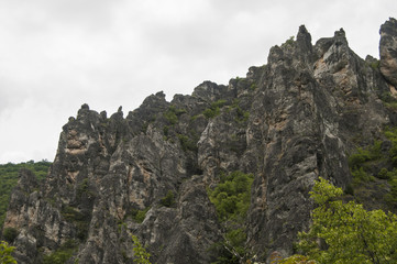 Eroded rocks in mountains against gray cloudy sky background