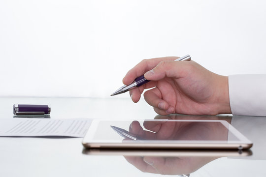 Businessman working on digital tablet on his desk with hand holding pen reflection.