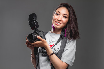 Happy Young Woman with modern digital Camera against a grey back