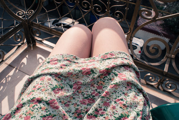 Legs (knees) of a young woman sunbathing on the beach, on a sunny day. Filtered image in faded, washed out, retro style; summer vintage concept. Can be used as a background. Personal perspective.