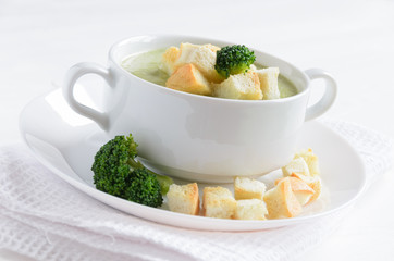 Broccoli soup with croutons on white table