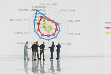 Selective focus of miniature businessman meeting and discuss with spider chart background as partnership and investment concept.