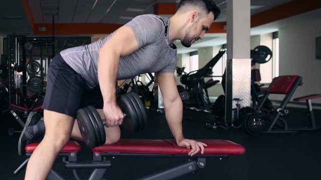 Young Male Athlete Exercising With Dumbbells In The Gym