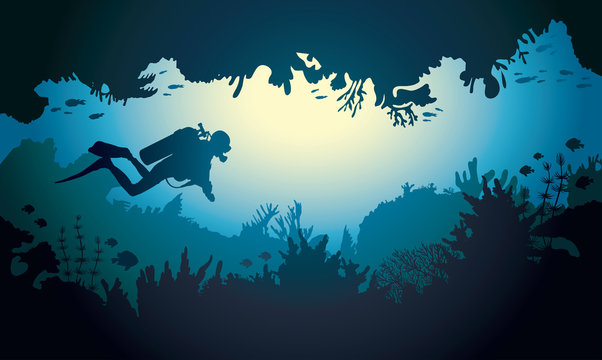 Silhouette of underwater cave with diver and coral reef.