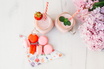 Strawberry milkshake and macaroons on wooden table