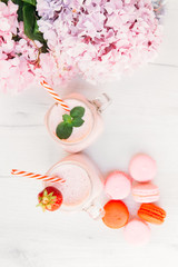 Fototapeta na wymiar Strawberry milkshake and macaroons on wooden table