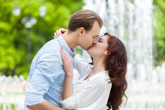 Passionate romantic young couple kissing and embracing in a green park