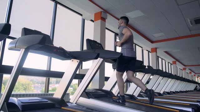 Young Male Athlete Running On Treadmill In The Gym