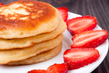 fritters on a plate with strawberries wooden background