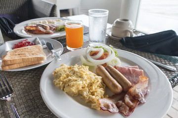 Large hot breakfast with scrambled eggs,  bacon, sausage served