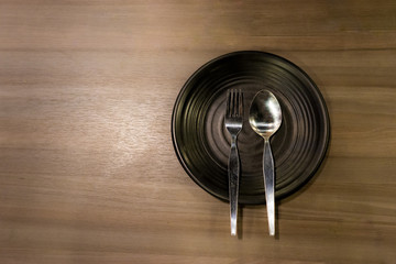 Empty plate with spoon and fork on wooden background