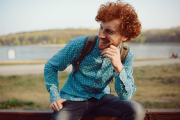 Outdoor portrait of young handsome smiling ginger man