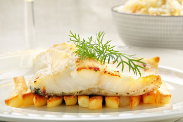 Baked fish and chips on white plate