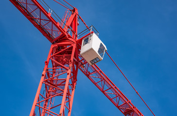 Red industrial construction crane against blue sky