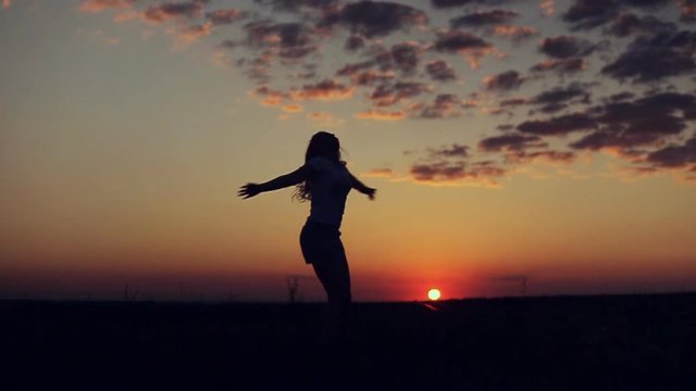 silhouette of happy girl turn on sunset background