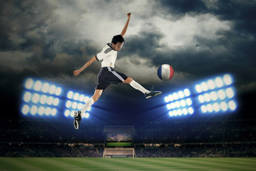 Fototapeta na wymiar Football player jumping while kicking a ball