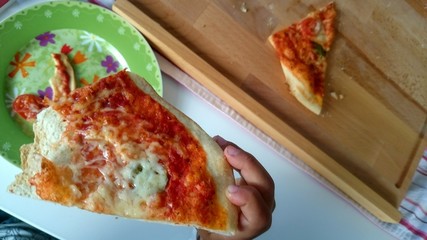 Kinderhand hält Pizza Stück