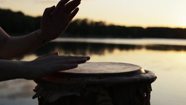игра на джембе или атабаке на фоне природы во время заката