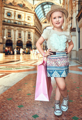 Happy little fashion monger with pink shopping bag in Galleria
