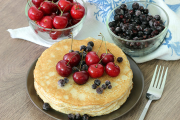 Homemade delicious pancakes. Closeup of pancakes with fresh blueberry and nuts on wooden background. Stack of  pancakes with nuts and maple syrup on plate and napkin. Selective focus