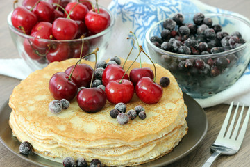 Homemade delicious pancakes. Closeup of pancakes with fresh blueberry and nuts on wooden background. Stack of  pancakes with nuts and maple syrup on plate and napkin. Selective focus