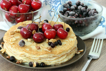 Homemade delicious pancakes. Closeup of pancakes with fresh blueberry and nuts on wooden background. Stack of  pancakes with nuts and maple syrup on plate and napkin. Selective focus