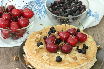 Homemade delicious pancakes. Closeup of pancakes with fresh blueberry and nuts on wooden background. Stack of  pancakes with nuts and maple syrup on plate and napkin. Selective focus
