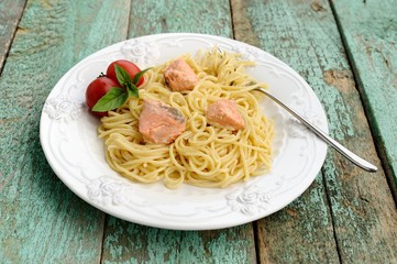 Portion of spaghetti with basil, tomatoes and red fish filet