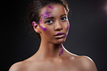 A beautiful dark-skinned woman with paint on his face. Beauty, fashion, portrait. Creative make-up close-up.