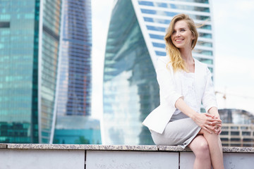 Young woman sitting in front of city buildings.