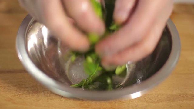 Fresh ruccola mixed with oil in metal bowl