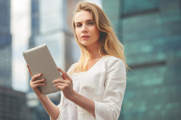 Beautiful woman using electronic tab in the street