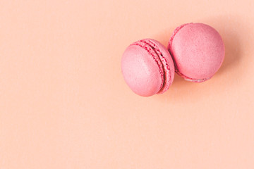 pink macaroon on beige paper background, top view, flat lay