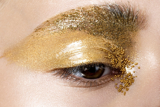 Closeup image of beautiful woman eye with gold makeup