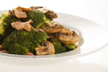 Broccoli sauteed with bacon, onion and mushrooms in white plate