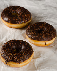 chocolate glazed donuts on crumbled baking paper
