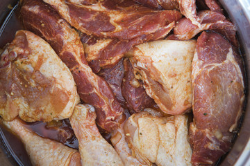 pieces mixed raw meat marinating in a steel pot