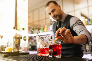 Barman is making cocktail at night club.
