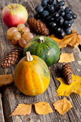 seasonal pumpkin, apple and grapes with autumn leaves, closeup,