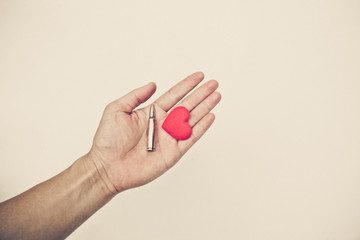 Hand holding a bullet and a red heart - Stop war and violence concept
