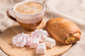 sweet buns, meringues and coffee cup on a wooden board