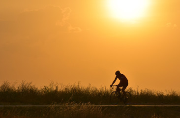 Obraz na płótnie Canvas Cyclist riding bicycle on sunset sky, silhouette.