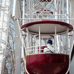 Sad girl on a Ferris wheel at amusement park, winter cold depres