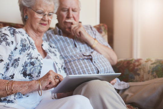 Elderly couple at home using digital tablet