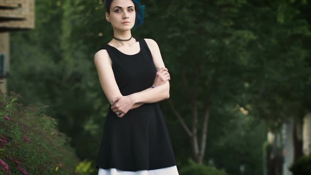 Pretty punk girl with tattooed legs standing on the street.