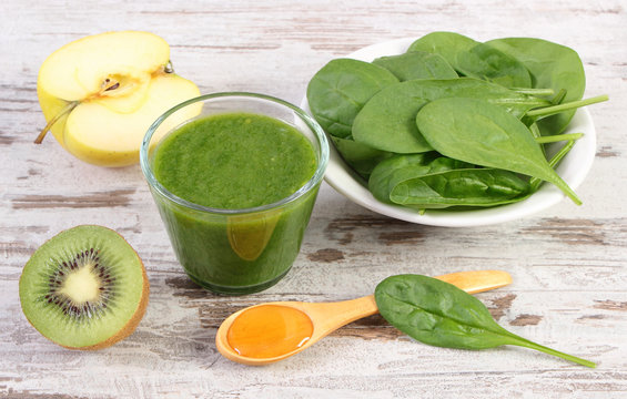 Ingredients and fresh cocktail from spinach, apple and kiwi on wooden background, healthy nutrition