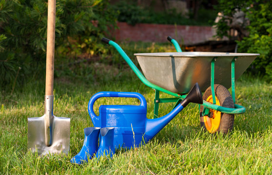 Garden tools on a green lawn. watering can and rubber boots.